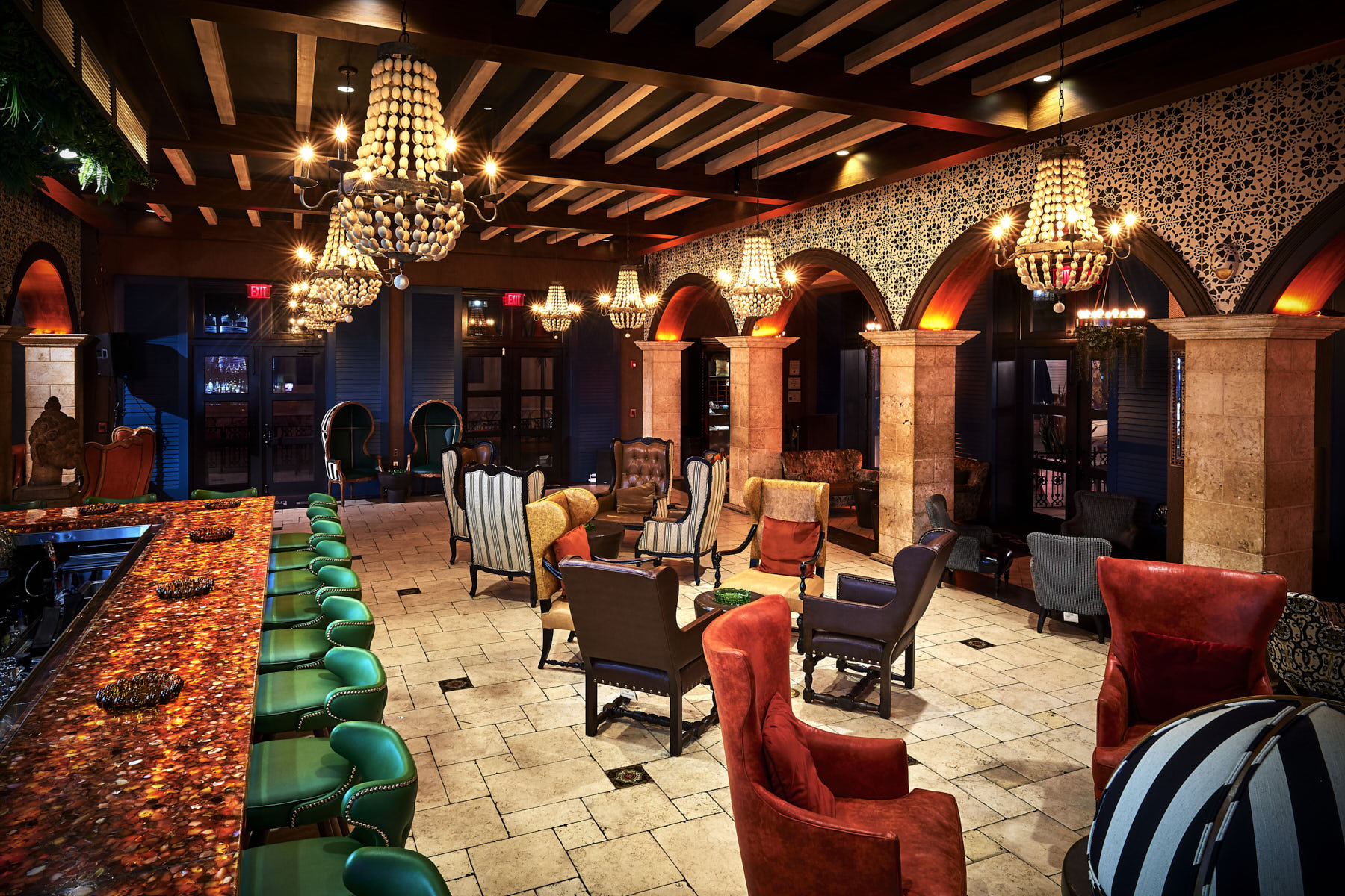 A cigar lounge interior — vaulted ceilings, chandeliers, leather seating in low evening light.